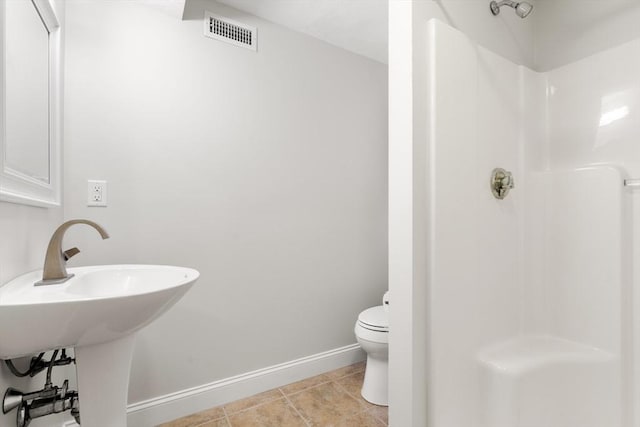 bathroom featuring baseboards, visible vents, toilet, tile patterned floors, and walk in shower