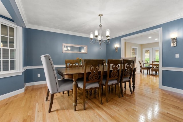 dining space with ornamental molding, light wood-style flooring, and baseboards