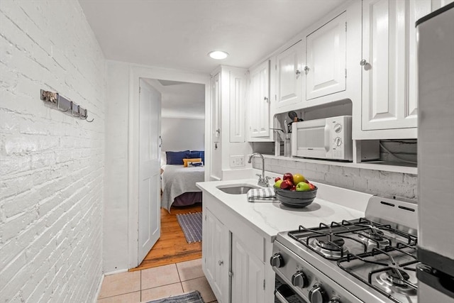 218 Washington St Unit 5, Marblehead, MA 01945 - kitchen with range with gas stovetop, light tile patterned floors, a sink, white cabinetry, and white microwave
