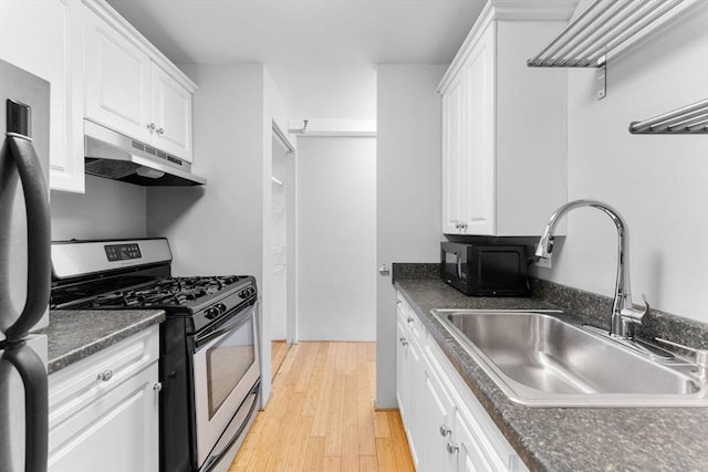 42 8th St Unit 1301, Boston, MA 02129 - kitchen with stainless steel gas range oven, under cabinet range hood, a sink, freestanding refrigerator, and dark countertops