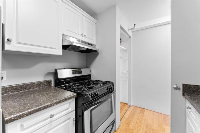 42 8th St Unit 1301, Boston, MA 02129 - kitchen with gas range, under cabinet range hood, dark countertops, white cabinetry, and light wood-style flooring