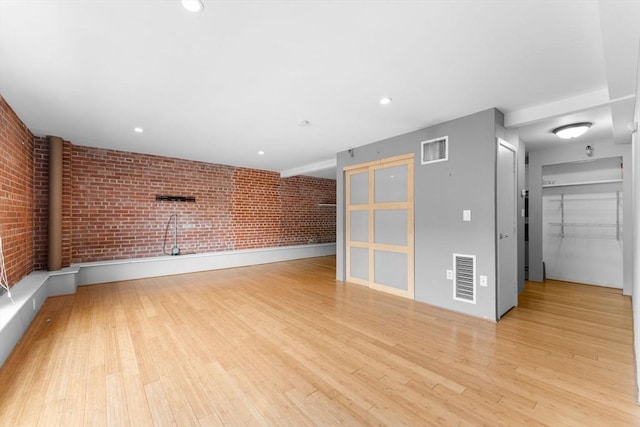 42 8th St Unit 1301, Boston, MA 02129 - unfurnished living room featuring brick wall, light wood-type flooring, and recessed lighting