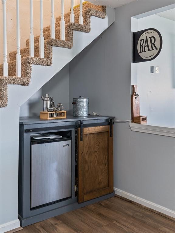 bar with baseboards, dark wood finished floors, and stairs