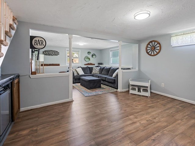 living room featuring a textured ceiling, baseboards, and wood finished floors
