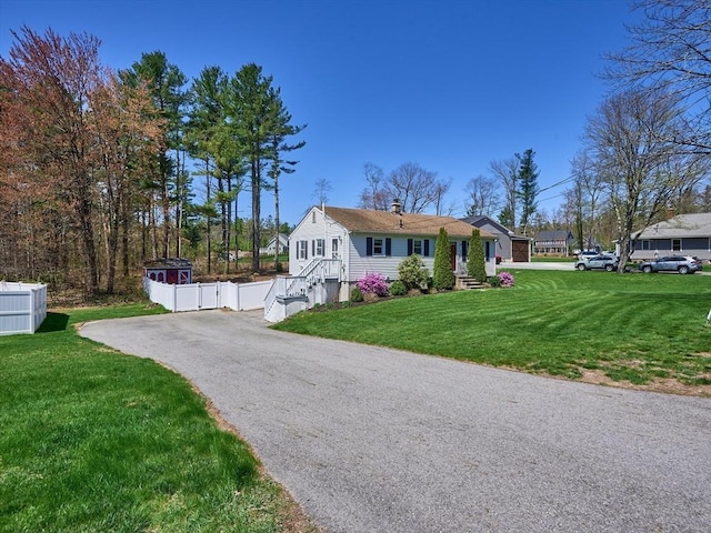 ranch-style house with fence, a chimney, driveway, and a front yard
