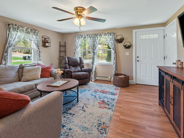 living room featuring a ceiling fan, baseboard heating, and light wood-style flooring