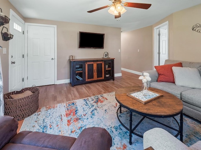 living area featuring baseboards, ceiling fan, and wood finished floors