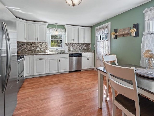 kitchen featuring white cabinets, stainless steel appliances, decorative backsplash, and light wood-style flooring