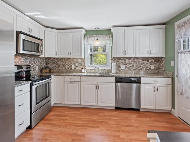 kitchen with a sink, appliances with stainless steel finishes, white cabinets, and light wood-style floors