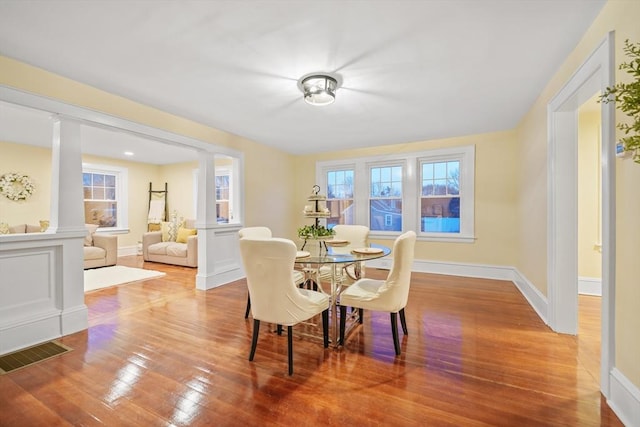 dining area with hardwood / wood-style floors and ornate columns