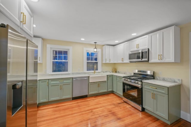 kitchen featuring sink, white cabinetry, decorative light fixtures, appliances with stainless steel finishes, and green cabinets