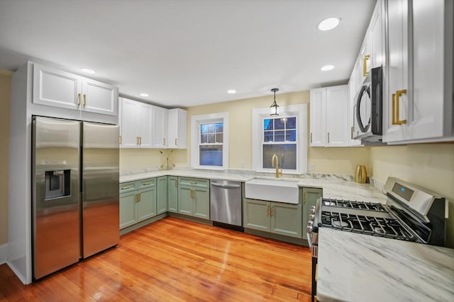 kitchen with green cabinetry, stainless steel appliances, sink, and white cabinets