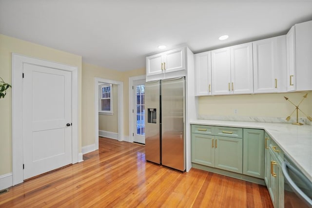 kitchen with light wood-type flooring, stainless steel appliances, white cabinets, and green cabinets