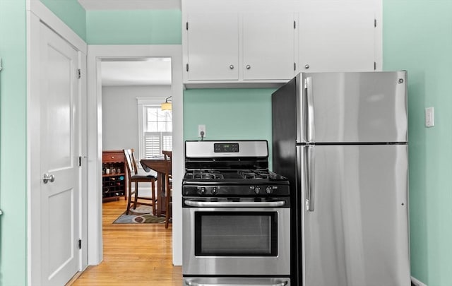 kitchen with appliances with stainless steel finishes, white cabinets, and light hardwood / wood-style floors