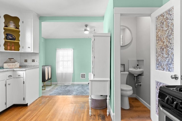 bathroom featuring hardwood / wood-style floors, backsplash, ceiling fan, and toilet