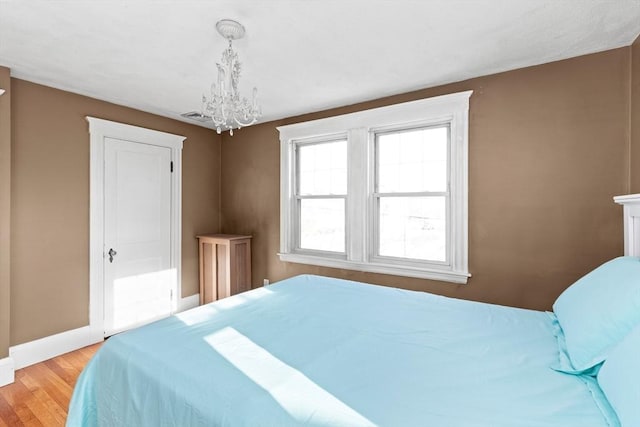 bedroom with an inviting chandelier and light hardwood / wood-style floors