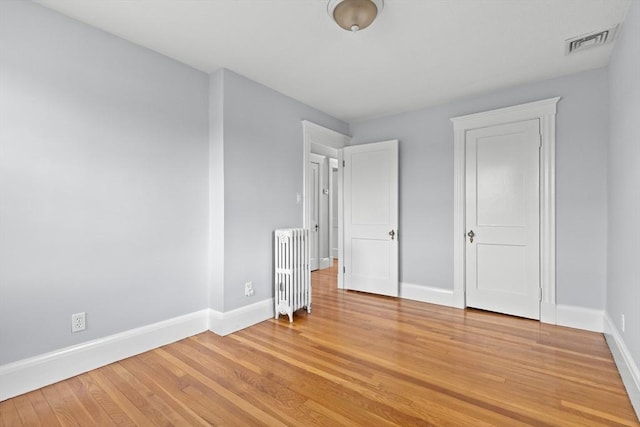 unfurnished bedroom featuring hardwood / wood-style flooring and radiator heating unit