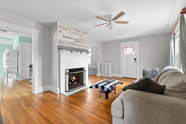 living room with ceiling fan, a healthy amount of sunlight, a fireplace, and light wood-type flooring