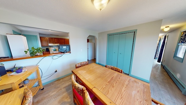 dining room with a baseboard heating unit and light wood-type flooring