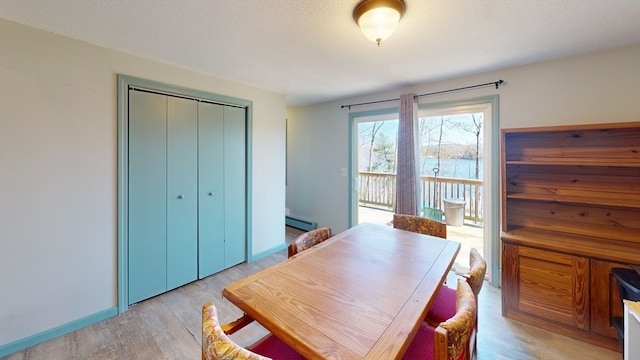 dining space with light hardwood / wood-style flooring and a baseboard heating unit