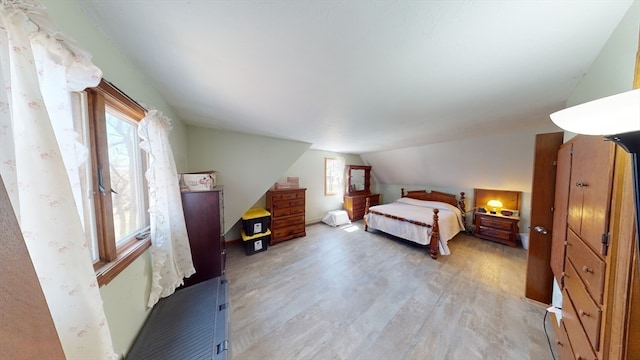 bedroom featuring light wood-type flooring and vaulted ceiling