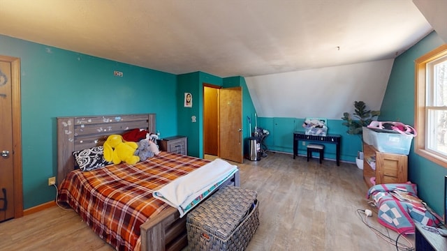 bedroom with light hardwood / wood-style flooring, multiple windows, and lofted ceiling