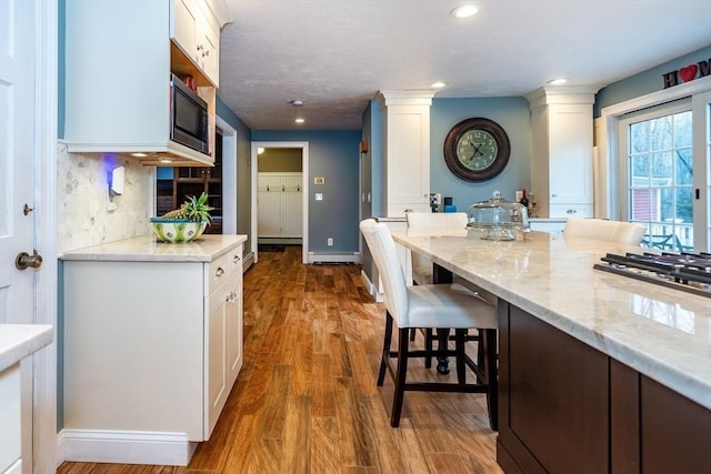 262 Homestead Ave, Rehoboth, MA 02769 - kitchen with ornate columns, white cabinetry, built in microwave, dark wood finished floors, and a breakfast bar