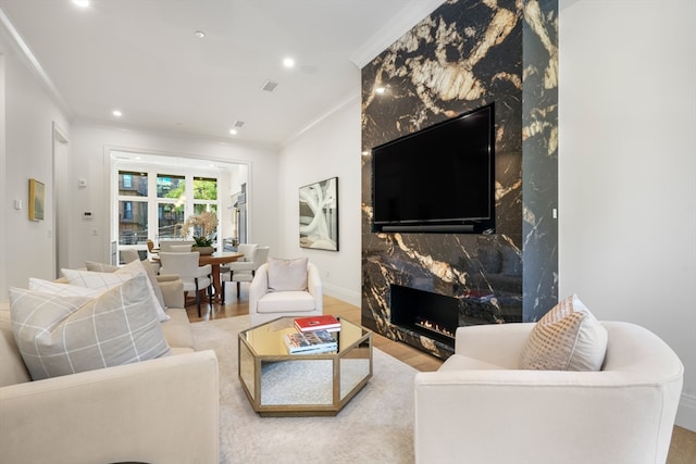 living room featuring light hardwood / wood-style floors, ornamental molding, and a fireplace