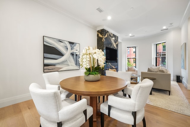 dining space featuring ornamental molding and light hardwood / wood-style flooring