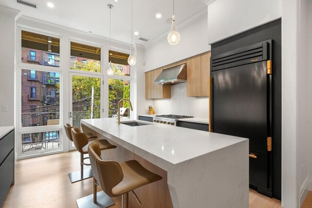 30 Concord Sq Unit 1, Boston, MA 02118 - kitchen featuring a kitchen island with sink, fridge, a sink, wall chimney exhaust hood, and modern cabinets