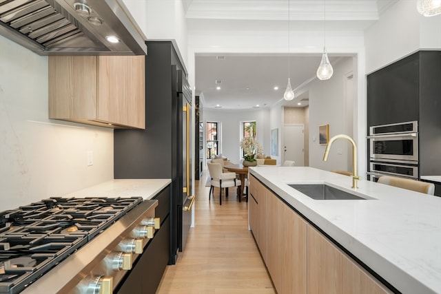 kitchen with light hardwood / wood-style flooring, sink, light stone counters, and hanging light fixtures