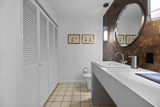 bathroom with tile patterned flooring, toilet, vanity, baseboards, and a closet