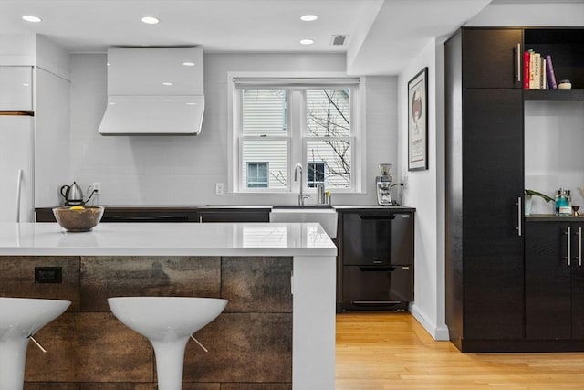 kitchen with dishwashing machine, modern cabinets, a sink, and light wood-style floors