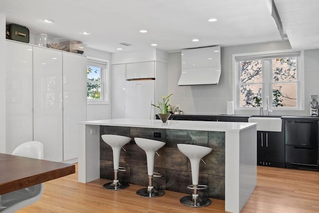 kitchen featuring refrigerator, light wood-style flooring, white cabinetry, modern cabinets, and a kitchen breakfast bar