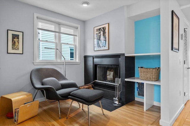 sitting room with light wood finished floors, a fireplace with flush hearth, and baseboards