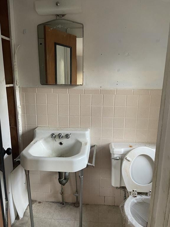 bathroom featuring toilet, tile patterned floors, tile walls, and sink