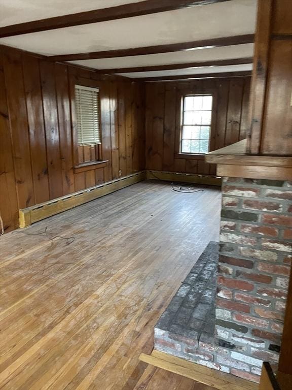 unfurnished room featuring beamed ceiling, wood walls, hardwood / wood-style flooring, and a baseboard radiator