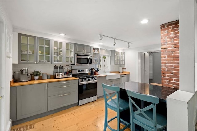 11 Congress St, Newburyport, MA 01950 - kitchen with appliances with stainless steel finishes, gray cabinets, light wood-style floors, and glass insert cabinets