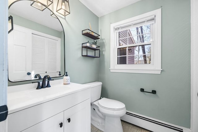 half bathroom with a baseboard heating unit, toilet, and vanity