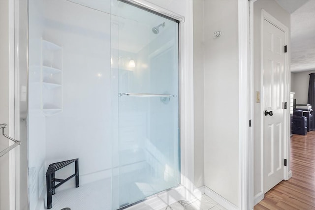 bathroom with wood finished floors and a stall shower