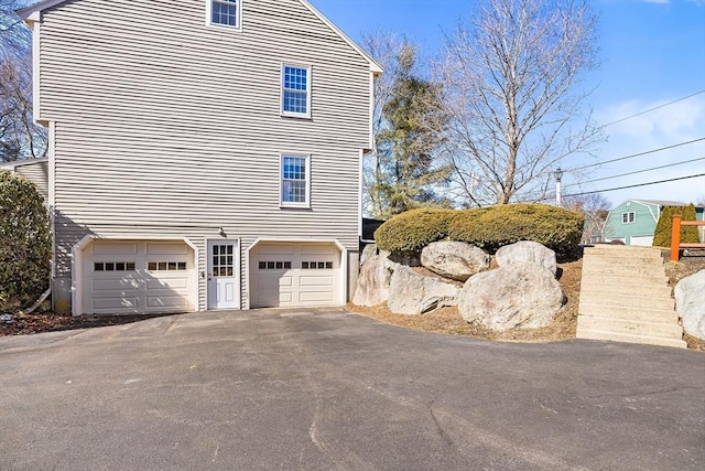 view of property exterior with an attached garage and driveway