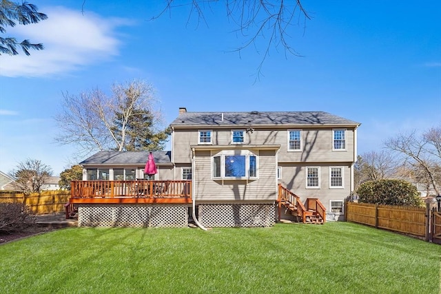 back of house featuring a deck, a lawn, a chimney, and a fenced backyard