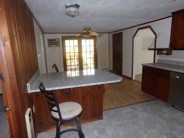 kitchen with dishwasher, light hardwood / wood-style flooring, a breakfast bar, a textured ceiling, and ceiling fan