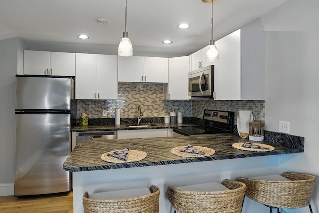 38 Moseley Ave Unit 5, Newburyport, MA 01950 - kitchen featuring stainless steel appliances, a peninsula, light wood-style flooring, decorative light fixtures, and decorative backsplash