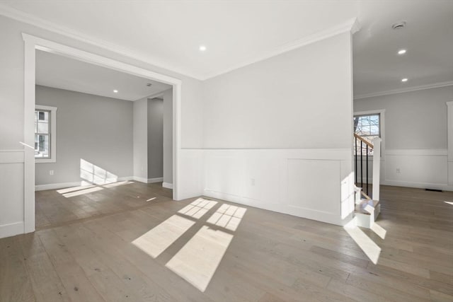 empty room featuring recessed lighting, wood finished floors, a wainscoted wall, and ornamental molding