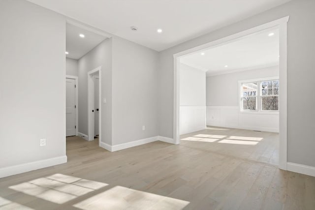spare room with recessed lighting, light wood-type flooring, crown molding, and baseboards