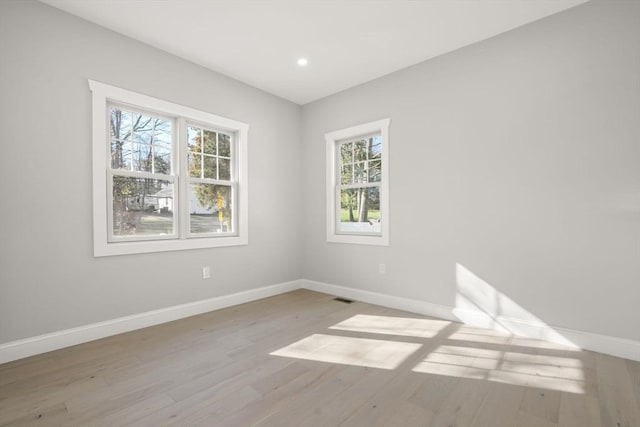 spare room featuring baseboards, a healthy amount of sunlight, wood finished floors, and recessed lighting