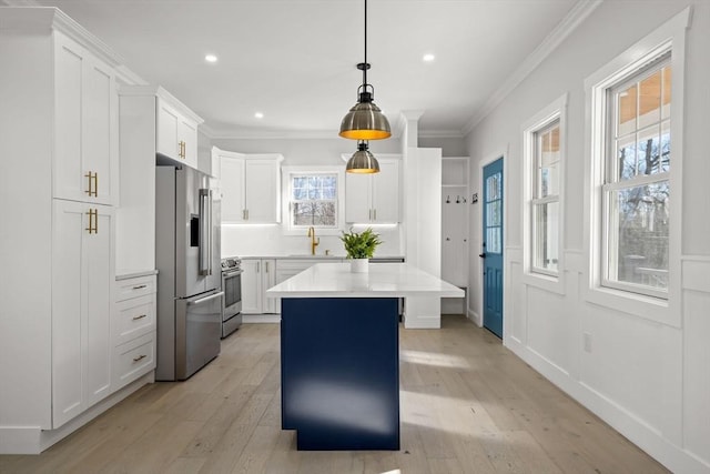 kitchen with crown molding, a sink, light countertops, stainless steel appliances, and light wood-style flooring