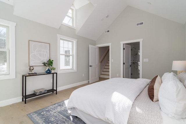 bedroom with baseboards, light wood-type flooring, visible vents, and high vaulted ceiling