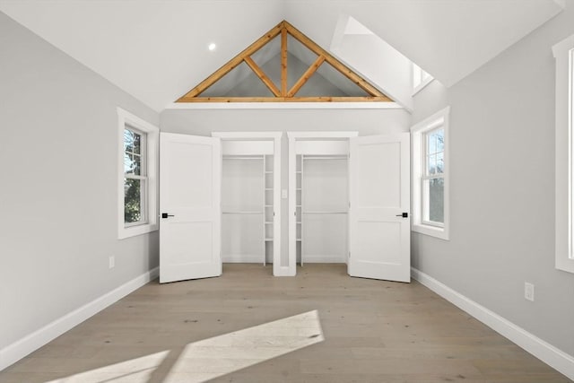 unfurnished bedroom featuring high vaulted ceiling, baseboards, wood finished floors, and recessed lighting